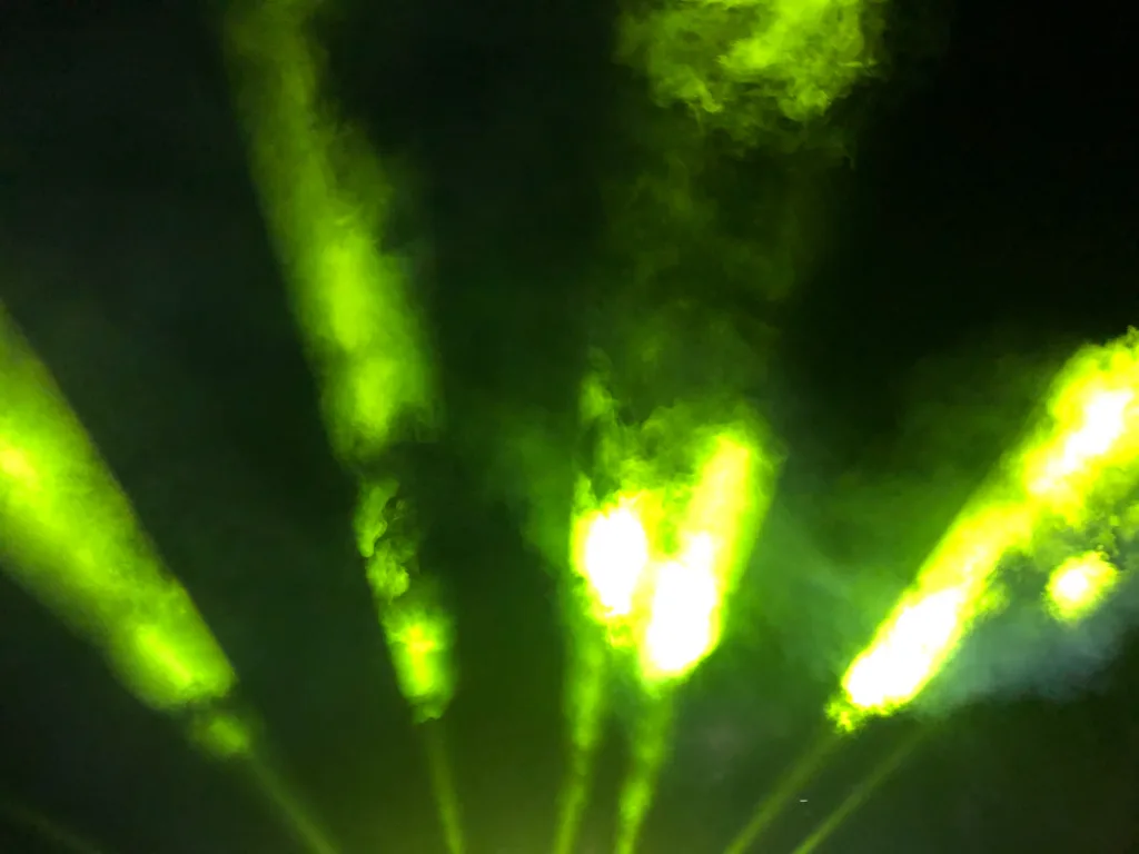 Grüne Laserstrahlen über der Piste bei Nacht.